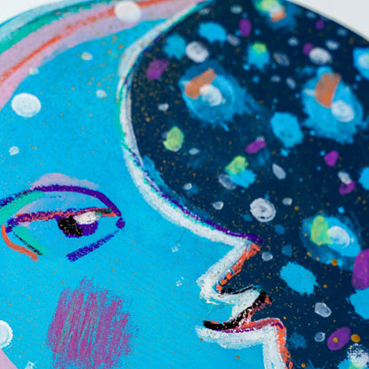 Colorful abstract painting of a moon face with a blue background